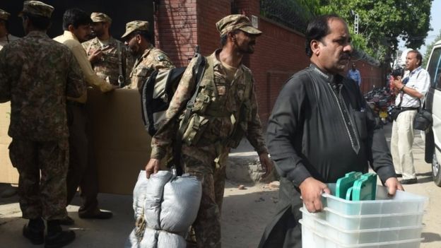 Pakistani soldiers help a polling officer carry election materials in Lahore (16 September 2017)