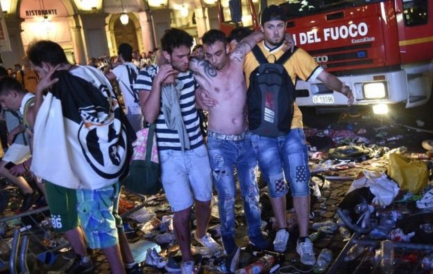 Herido saliendo de la plaza San Carlo, en Turín, con ayuda de dos personas.