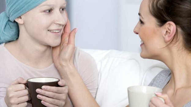 Una mujer con cáncer y una amiga tomando café.