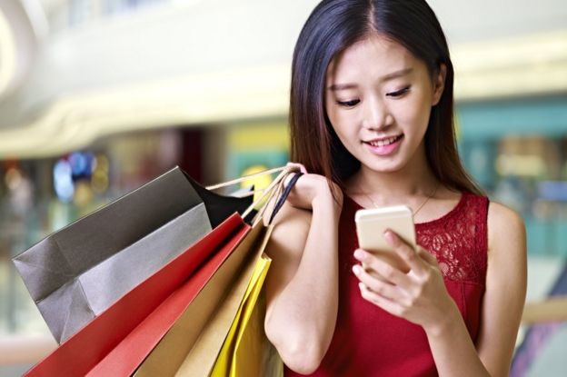 Young woman using phone while shopping