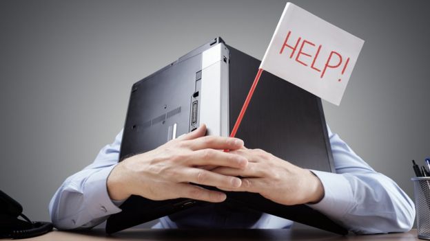 Un hombre estresado bajo una laptop pide ayuda