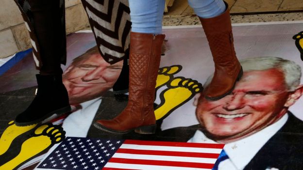 Palestinos caminando sobre un póster de Donald Trump y Mike Pence en diciembre.