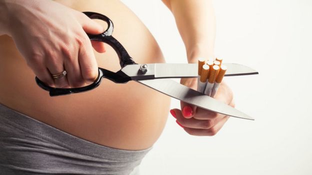 pregnant woman cutting up some cigarettes