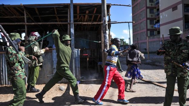 An anti-riot policeman beats a man with a stick as police flushes out opposition supporters, who had taken cover in a shack to escape teargas, during demonstrations in the Umoja subururb of Nairobi on November 28, 2017, following a denial of permission by police to the National Super Alliance (NASA) leader to hold a rally concurrently to the inauguration of the country's new president.