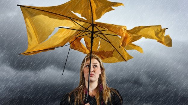 Mujer bajo la lluvia con paraguas roto