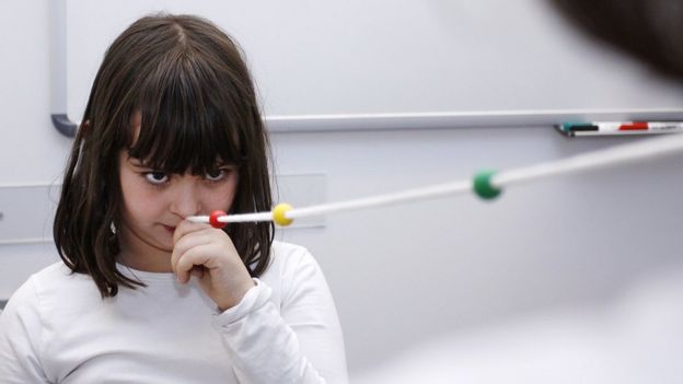 Niña haciendo un ejercicio de terapia visual con una cuerda de Brock.