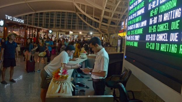 Passengers wait for flight information at Ngurah Rai airport in Bali