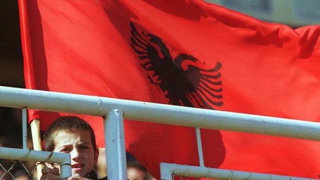 A young boy holds an Albanian flag October 21, 2000 as he watches a pre-election rally for the Democratic League of Kosovo