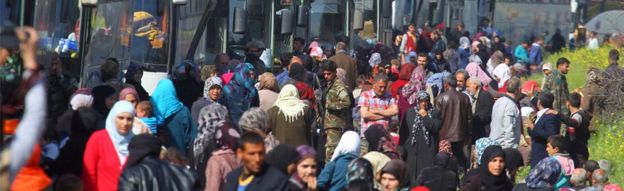 People that were evacuated from the two villages of Kefraya and al-Foua walk near buses, after a stall in an agreement between rebels and Syria's army