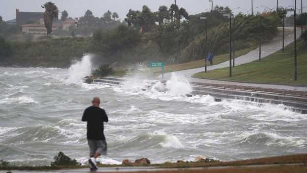 A man walks near the bay waters as they churn from approaching Hurricane Harvey on August 25, 2017 in Corpus Christi, Texas