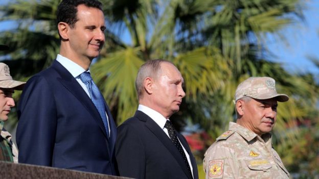 Syrian President Bashar al-Assad (L), Russian President Vladimir Putin (C), Russian Defence Minister Sergei Shoigu (R) visit the Hmeimim airbase in Syria (11 December 2017)