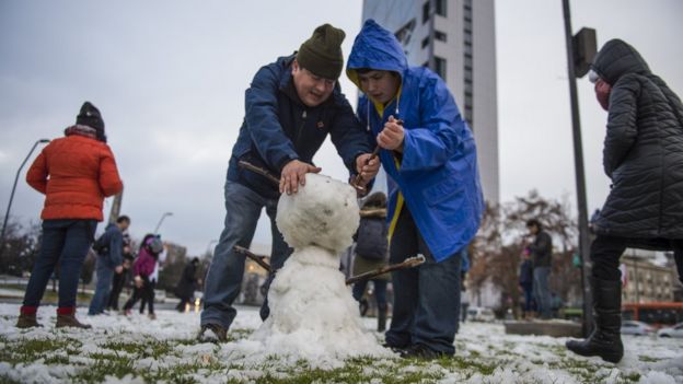 People make a snowman in Santiago on July 15, 2017