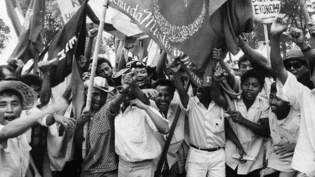 Young people holding flags with Arabic inscriptions
