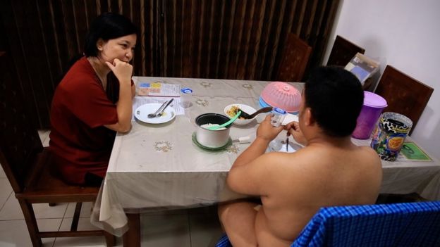 Aditya sentado desnudo en el comedor.