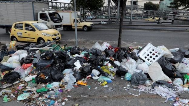 Vehicles drive by garbage bags left on a sidewalk in Bogota, Colombia, 07 February 2018