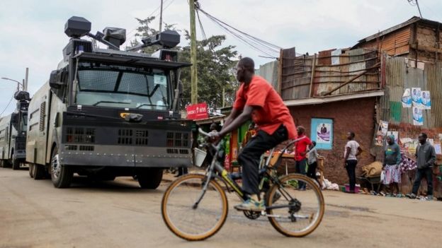 A man cycles past riot police water canons patrolling ahead of the Presidential election in Kibera slums of Nairobi, Kenya, 7 August 2017