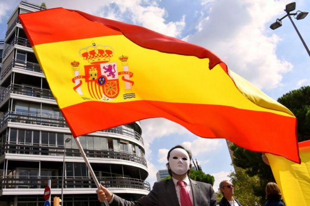 Hombre con una careta ondea la bandera española en protesta contra el referéndum por la independencia de Cataluña en Barcelona el 27 de septiembre.