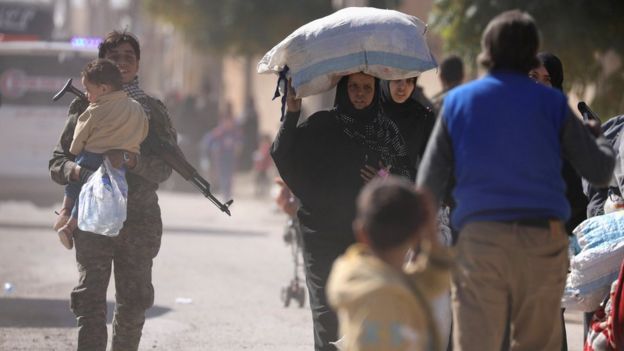 A woman holds her belongings as she flees Raqqa, Syria (16 October 2017)