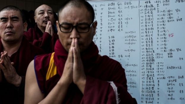 Monks pray near a collapsed building on February 7, 2016 in Tainan, Taiwan