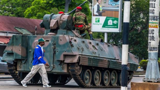 A man walks past an armoured personnel carrier in Harare on November 15, 2017