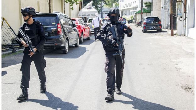 Police patrol around the Surabaya police headquarters after the blast on Monday