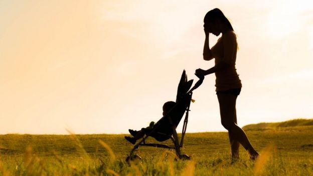 Mother with child in pushchair in field