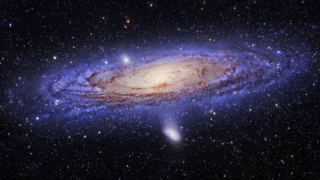 A spiral galaxy with blue/purple dust in its outer arms and reddish dust in its interior