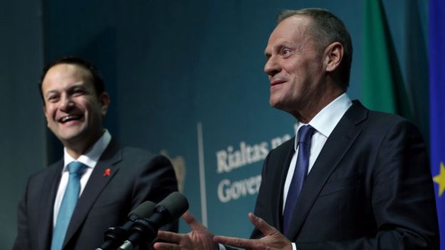 Leo Varadkar laughs as Donald Tusk, smiling, addresses the media from a podium