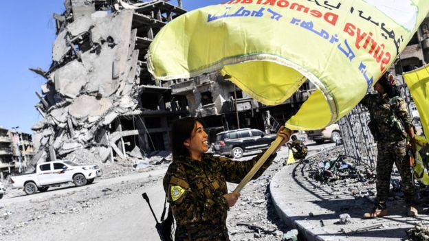Rojda Felat, a Syrian Democratic Forces (SDF) commander, waves the alliance's flag in central Raqqa on 17 October 2017