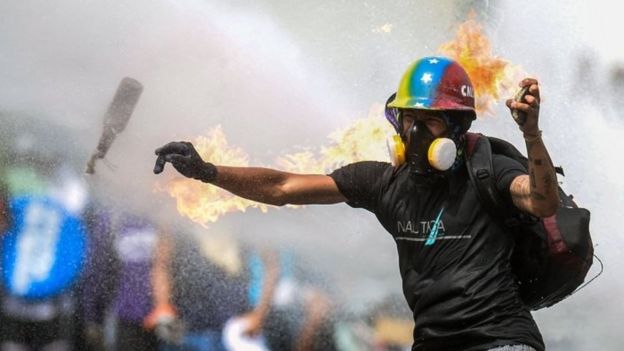 An opposition activist throws a molotov cocktail in clashes with riot police during a march by doctors and other health care personnel in Caracas, Venezuela, on May 22, 2017.