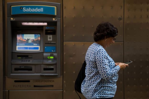 Mujer frente a un cajero del Banco Sabadell en Barcelona.