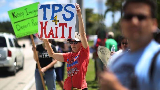 Mujer con pancarta pidiendo TPS para Haití.