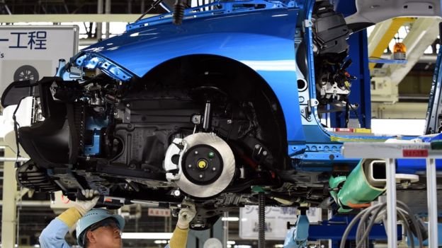 A man works on a Toyota Mirai vehicle on the production line