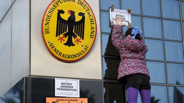 A girl puts a sign reading in German "Free our president" on the building of the German consulate during a demonstration in Barcelona on March 25, 2018