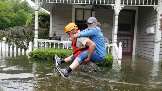 A Texas National Guard soldier carries a woman on his bank as they conduct rescue operations in flooded areas around Houston, Texas, U.S., August 27, 201