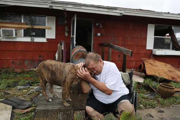 Hombre llora mientras sostiene a su perro entre las manos en Rockport, Texas, Estados Unidos, tras el paso del huracán Harvey.