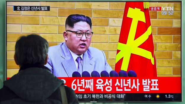 Um homem assistindo a um discurso de Kim Jong-un
