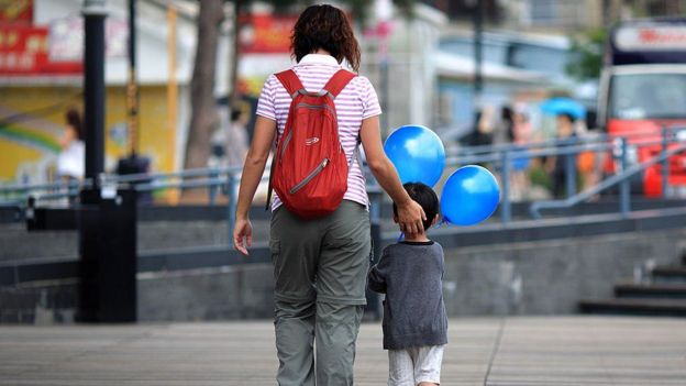 Mujer y niño caminando en la calle.