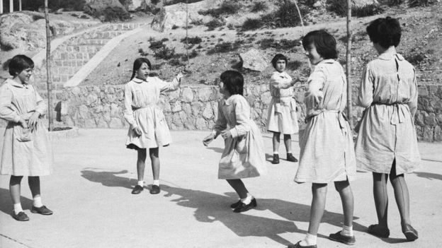 Un grupo de niñas jugando en el patio de un colegio.