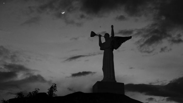 La estatua de un ángel en el cementerio, sobre el fondo del cielo nocturno.