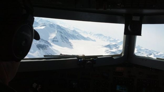 From the cockpit of the plane: a chain of snowy mountains with an ice-filled valley in between