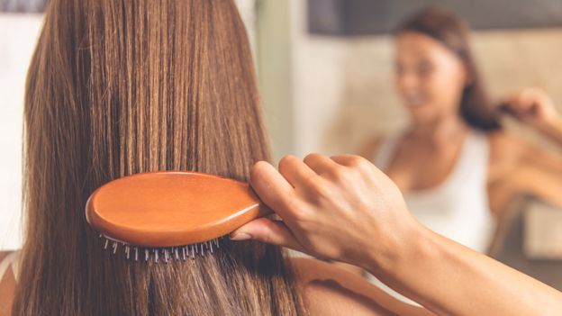 Una mujer se cepilla el pelo de espaldas