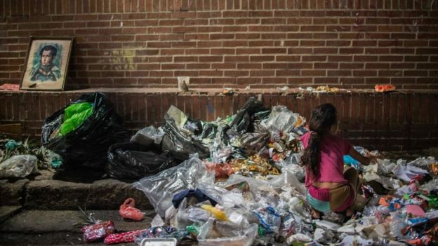Una niña escarbando entre la basura