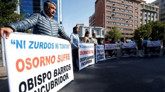 People hold banners reading "Neither lefties nor fools, Osorno suffers, Bishop Barros, accessory after the fact," during visit