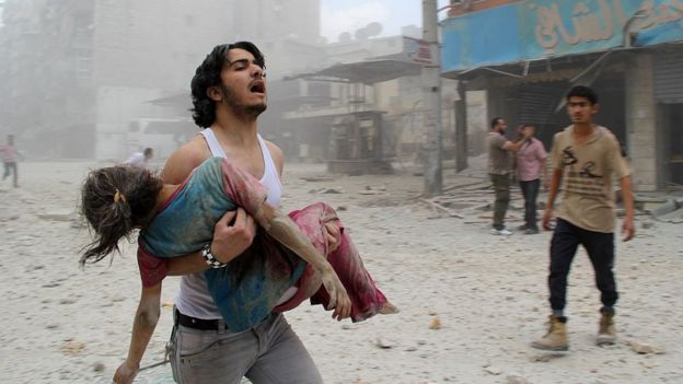 Hombre carga en brazos a una niña en Aleppo, Siria.