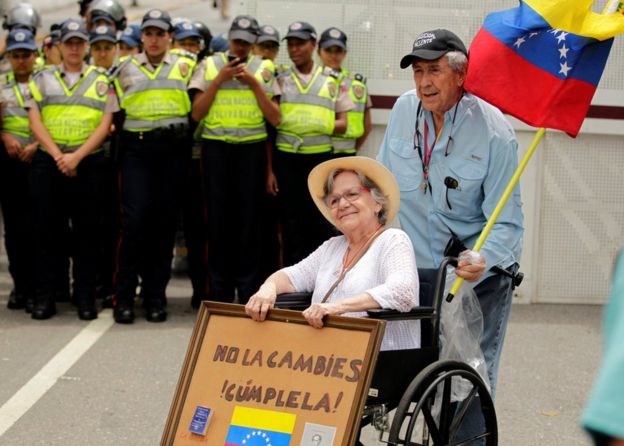 Mujer con el cartel con un mensaje a Maduro