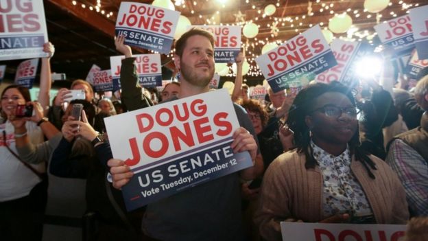 Supporters of Doug Jones listen as he speaks at a rally at Old Car Heaven in Birmingham, Alabama, on 11 December, 2017.