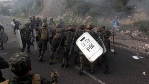 Soldiers push a garbage container settled to block a road by opposition supporters during a protest over a disputed presidential election in Tegucigalpa, Honduras December 11, 2017.