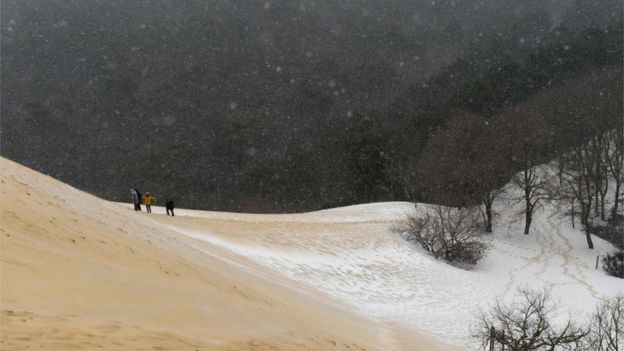 People walk on the partially snow covered Pyla sand dune after snow fall on 28 February 2018 in La Teste-de-Buch, south-west France
