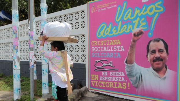 Una mujer pasa frente a un letrero de campaña de Daniel Ortega.